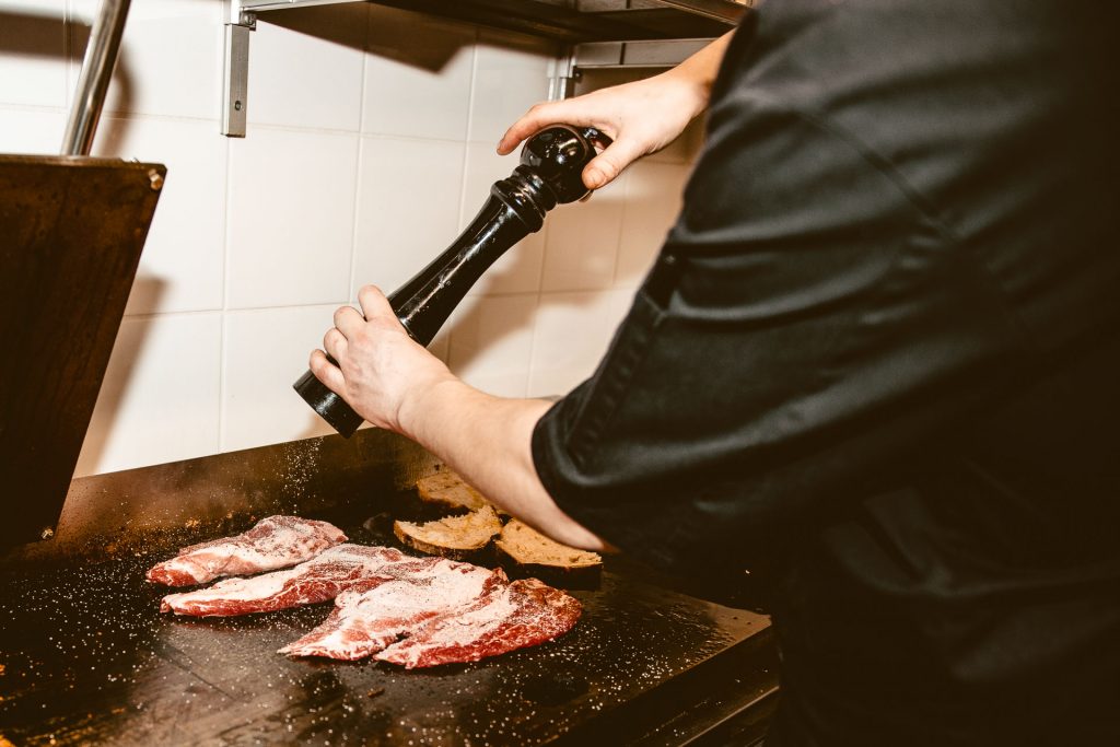 Kokki rouhii pippuria grillatun lihan päälle di Trevin keittiössä